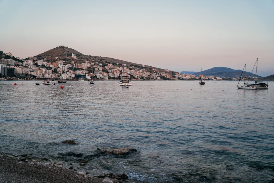 Boats in Sarandë bay below the hillside town at dusk